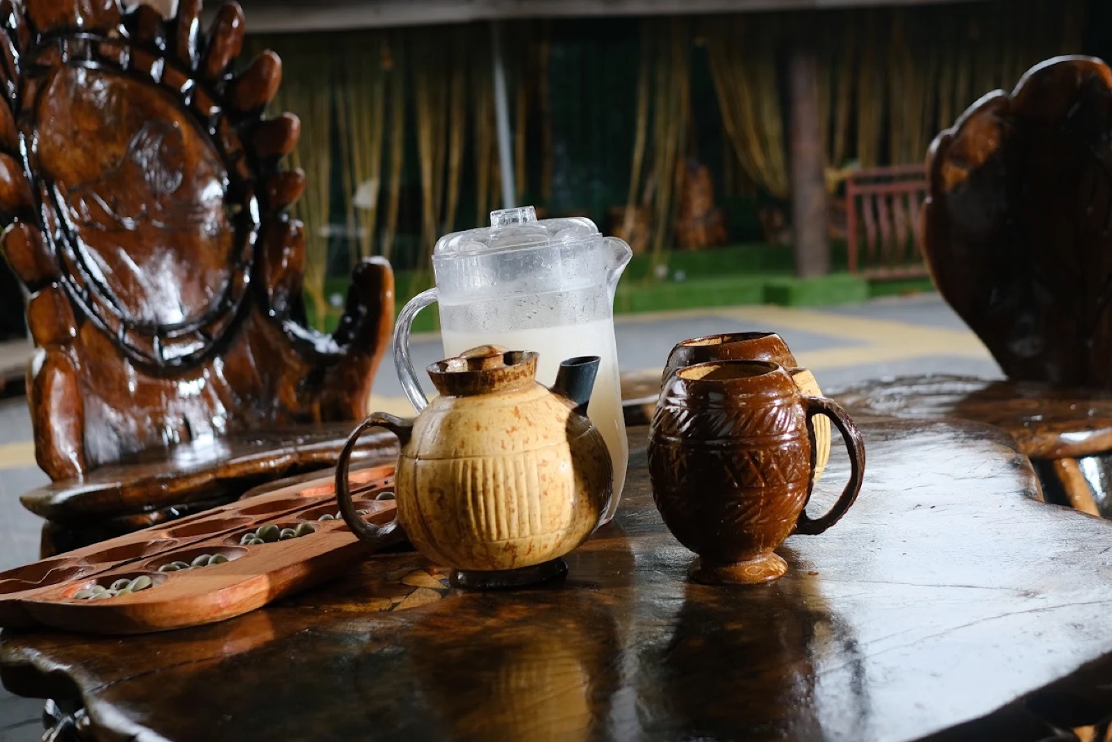 Palm wine in local cups, served on the Yard's wooden table with an ayo board